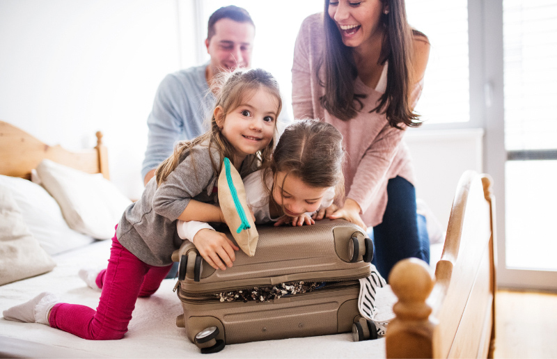 Happy family with two girls packing a suitcase for vacation
